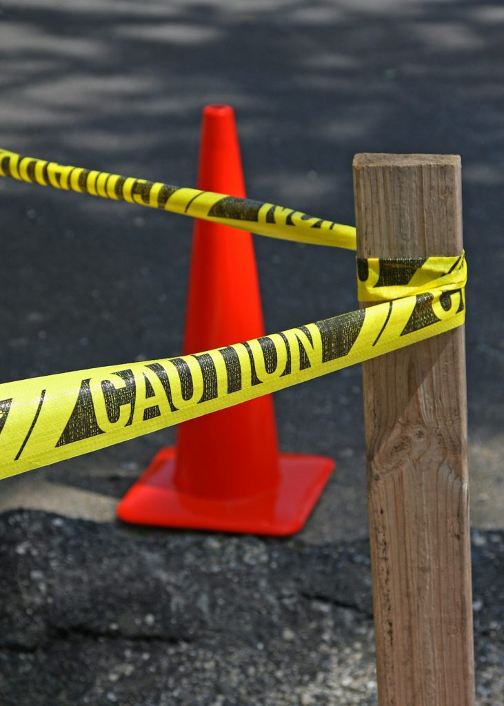 Caution tape tied to a post beside a cone