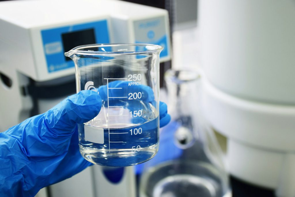 Gloved hand holding a lab beaker
