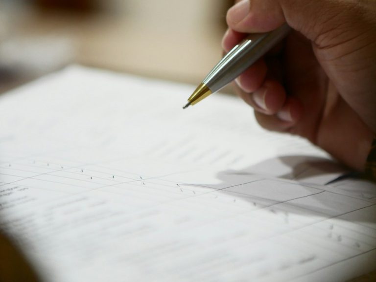Hand holding a pen over paperwork