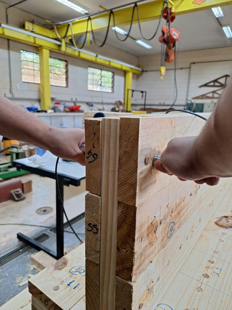Hands assembling wooden beams with metal fasteners