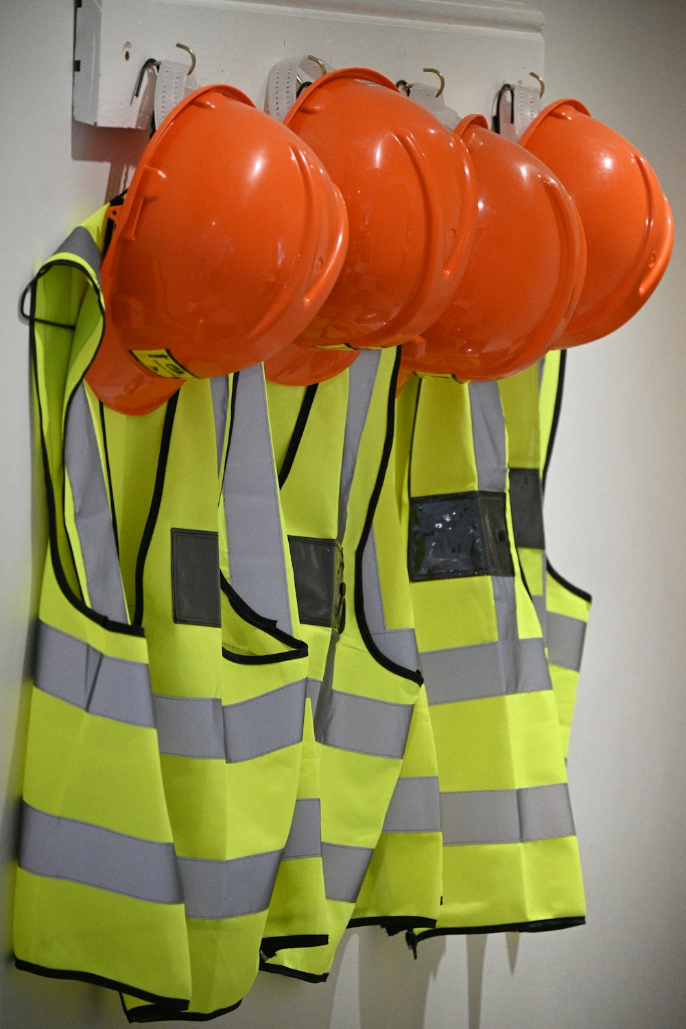 Hard hats and high-visibility vests hanging on a wall
