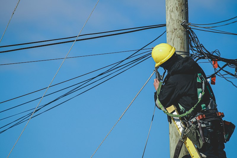 Lineman in a hard hat climbing a pole