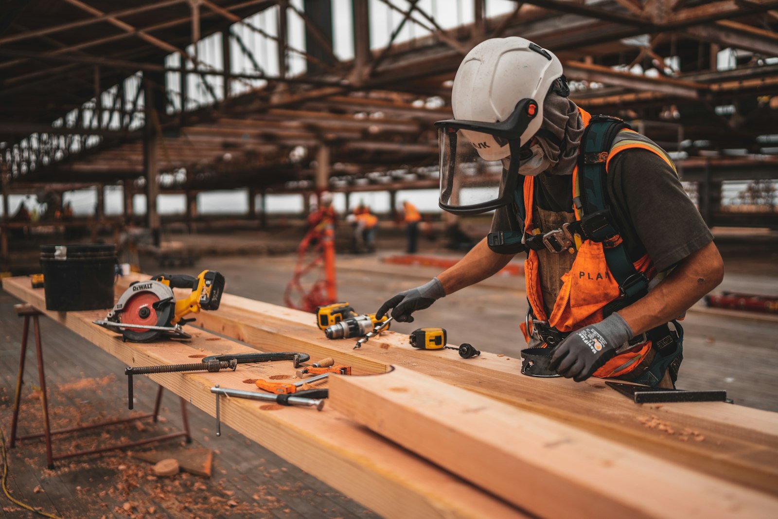 Worker in a safety vest and white hard hat using a power tool