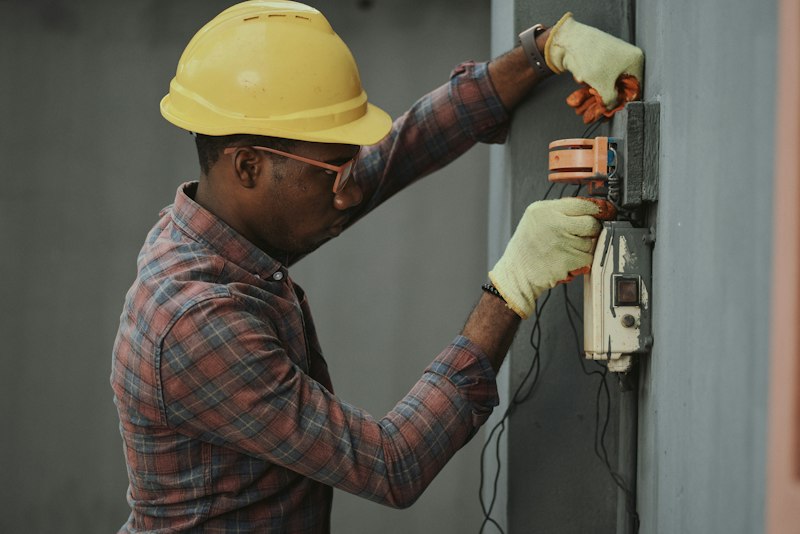 Tradesman in a yellow hard hat holding a tool