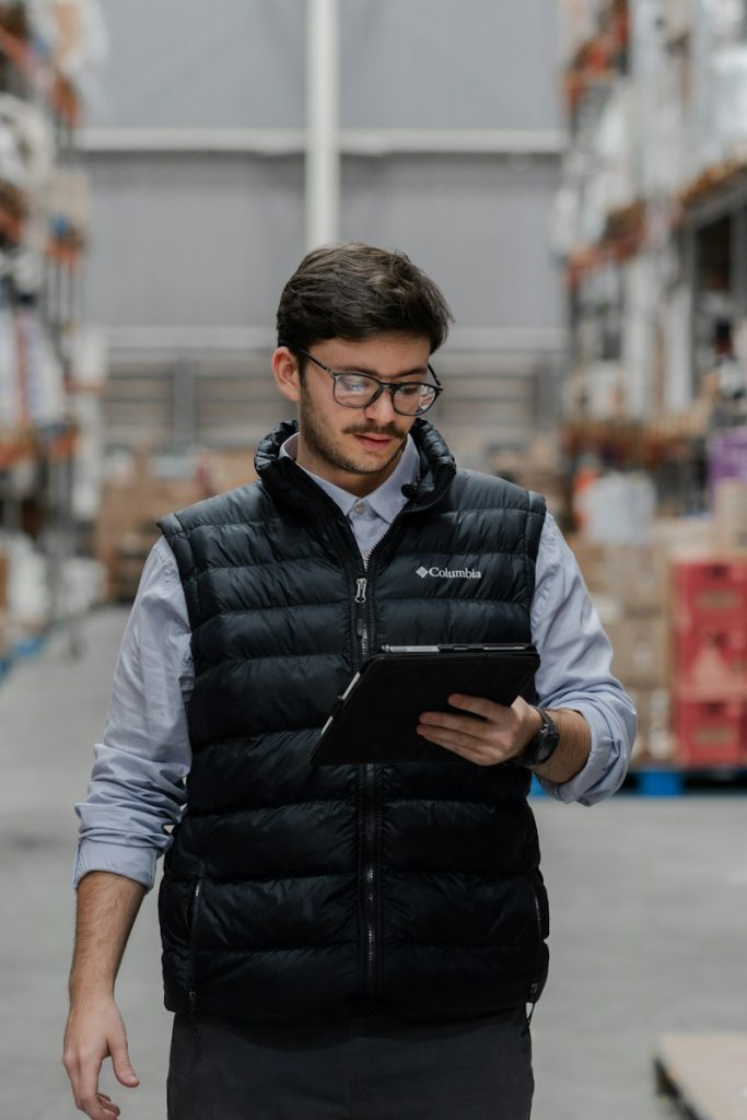 Worker in a vest using a tablet in a warehouse