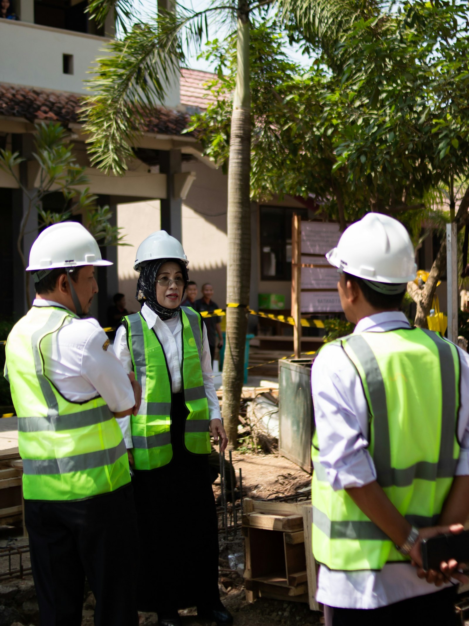 Three workers in hard hats and vests talking